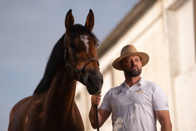Dr. Ștefan Răileanu ținând de căpăstru un cal murg, pe cer albastru